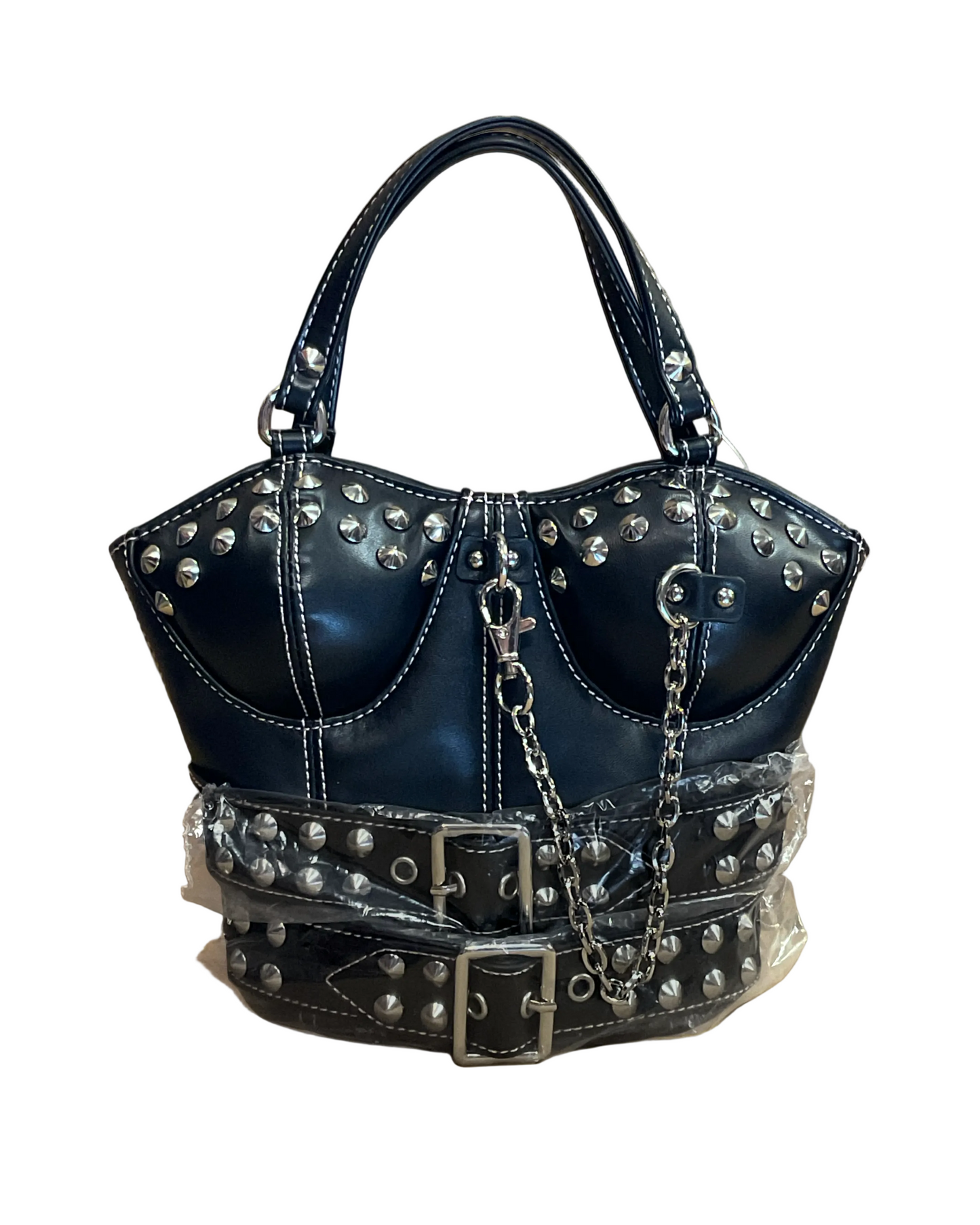 A structured black faux-leather handbag with silver studs, double top handles, a chain strap, and a wide studded belt detail wrapped in protective plastic, set against a plain brown paper background.